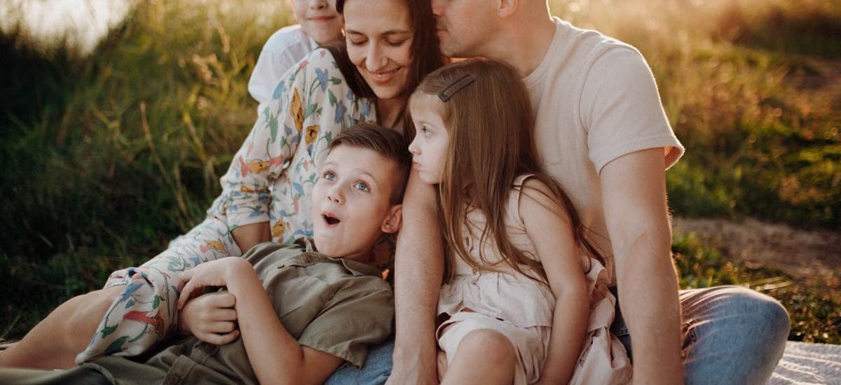 A joyful family enjoying quality time together on a sunset-lit meadow.