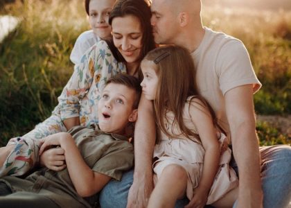 A joyful family enjoying quality time together on a sunset-lit meadow.