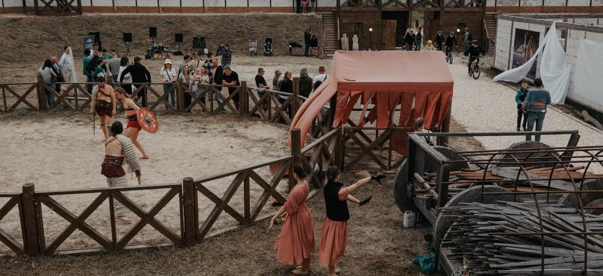 Lively medieval reenactment event featuring gladiators and spectators in outdoor arena.