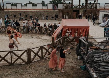 Lively medieval reenactment event featuring gladiators and spectators in outdoor arena.